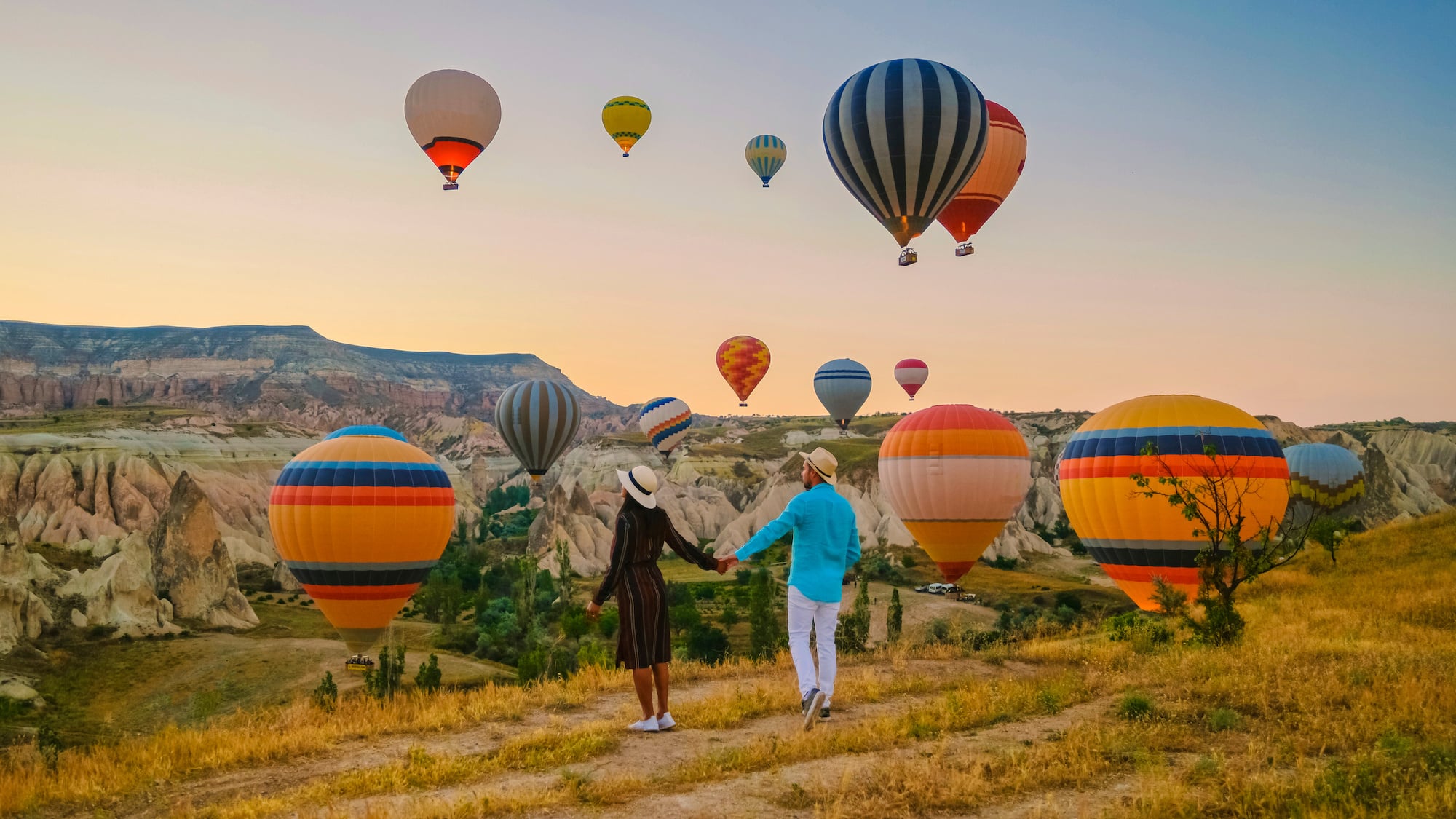 a young couple staring over a vista of vibrant hot air balloons