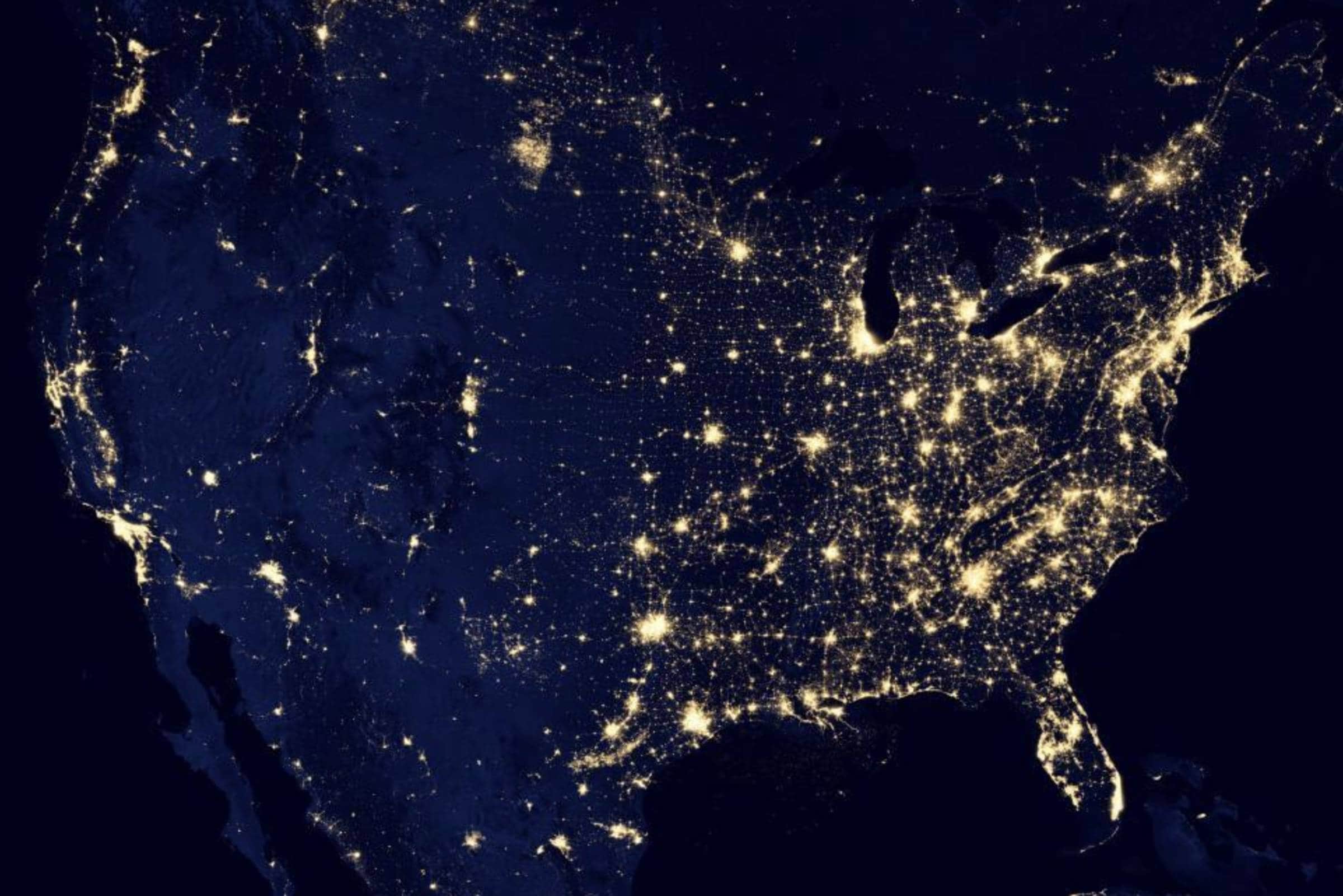 Night satellite view of the United States with glowing city lights.