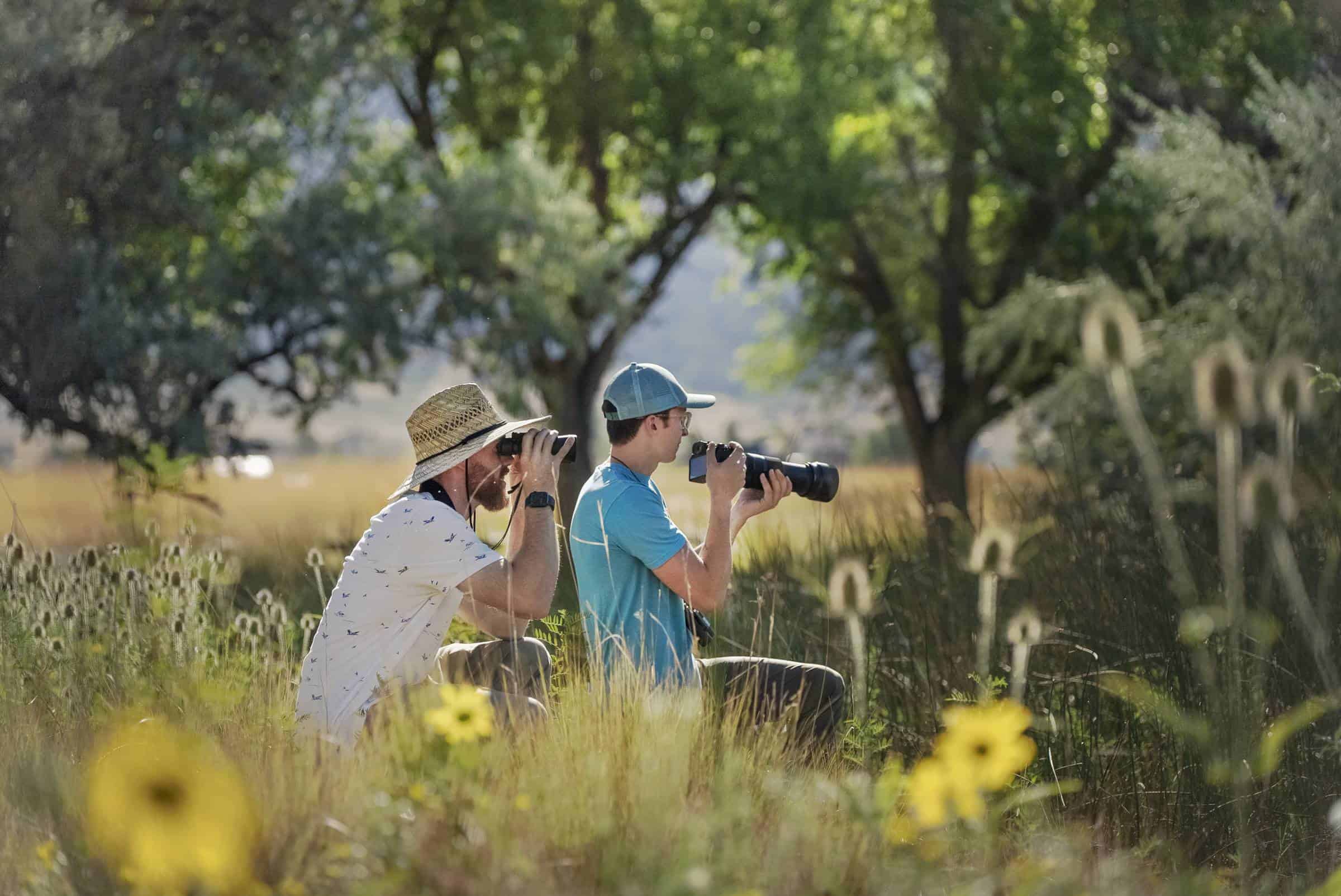 Two young men birding in meadow